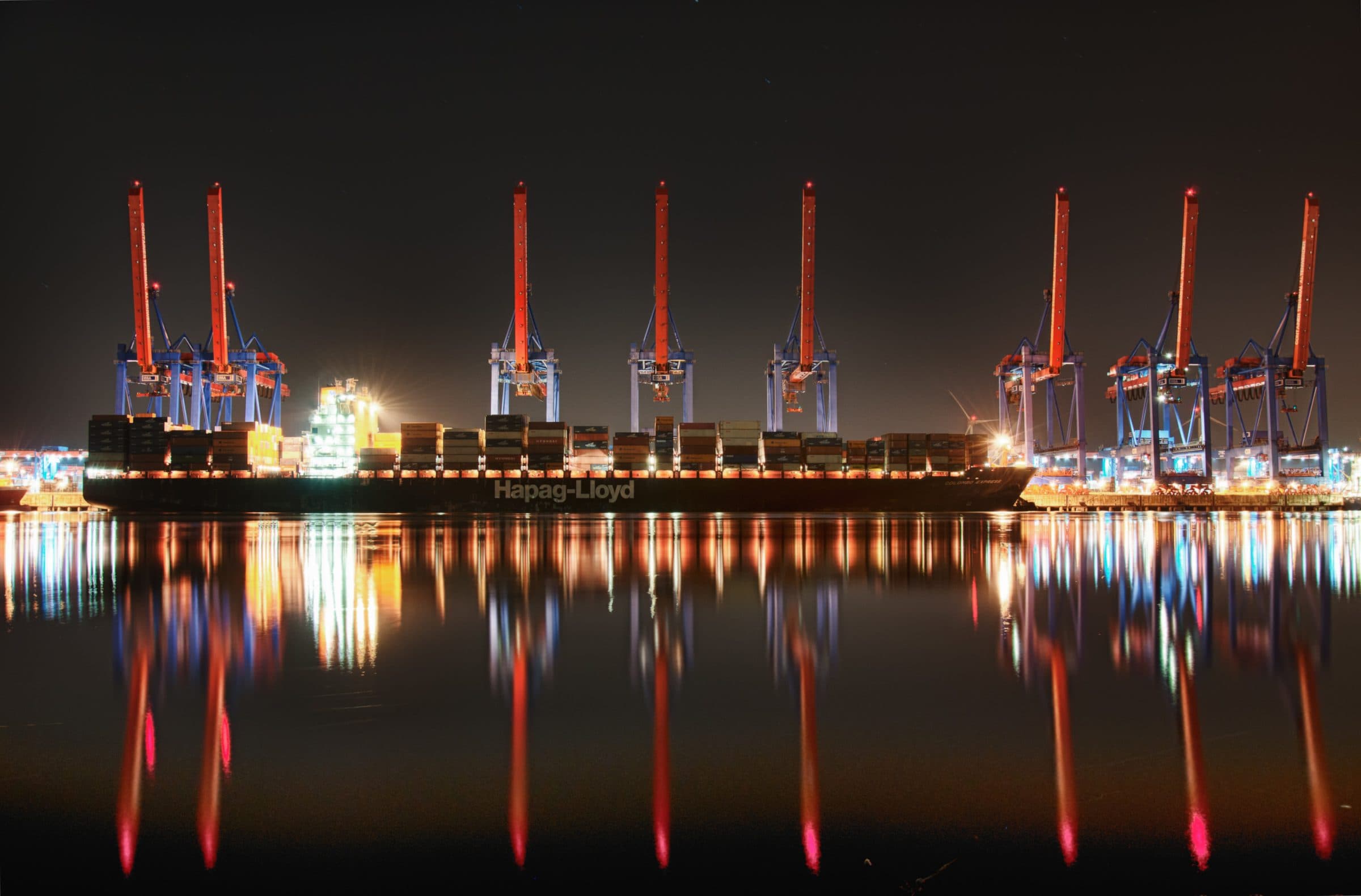 Container ship under working cranes at night